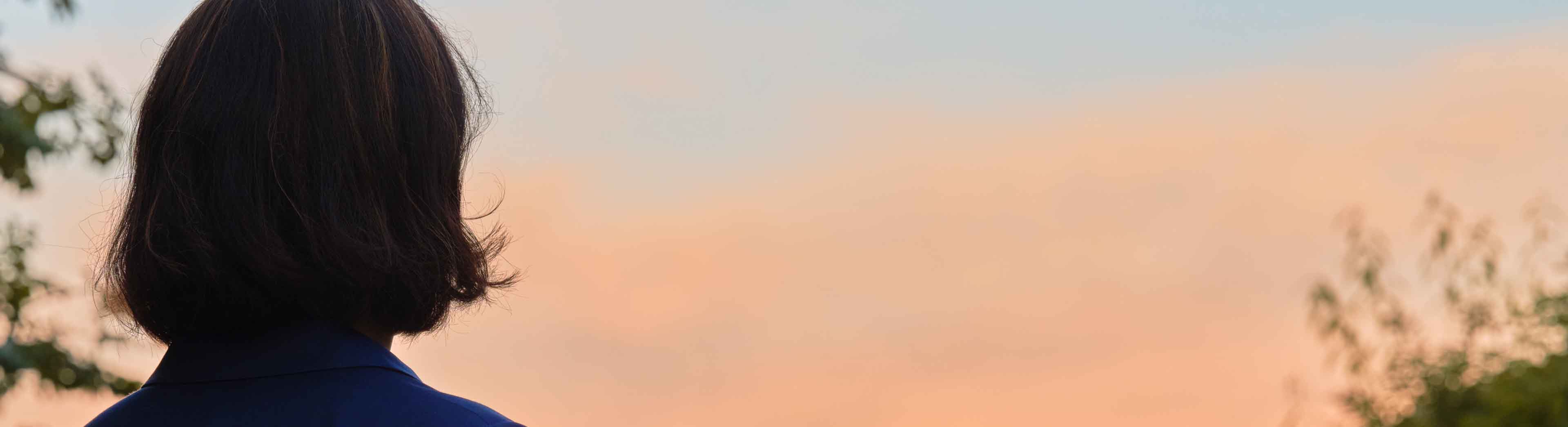 woman from behind viewing towards a red sunset sky